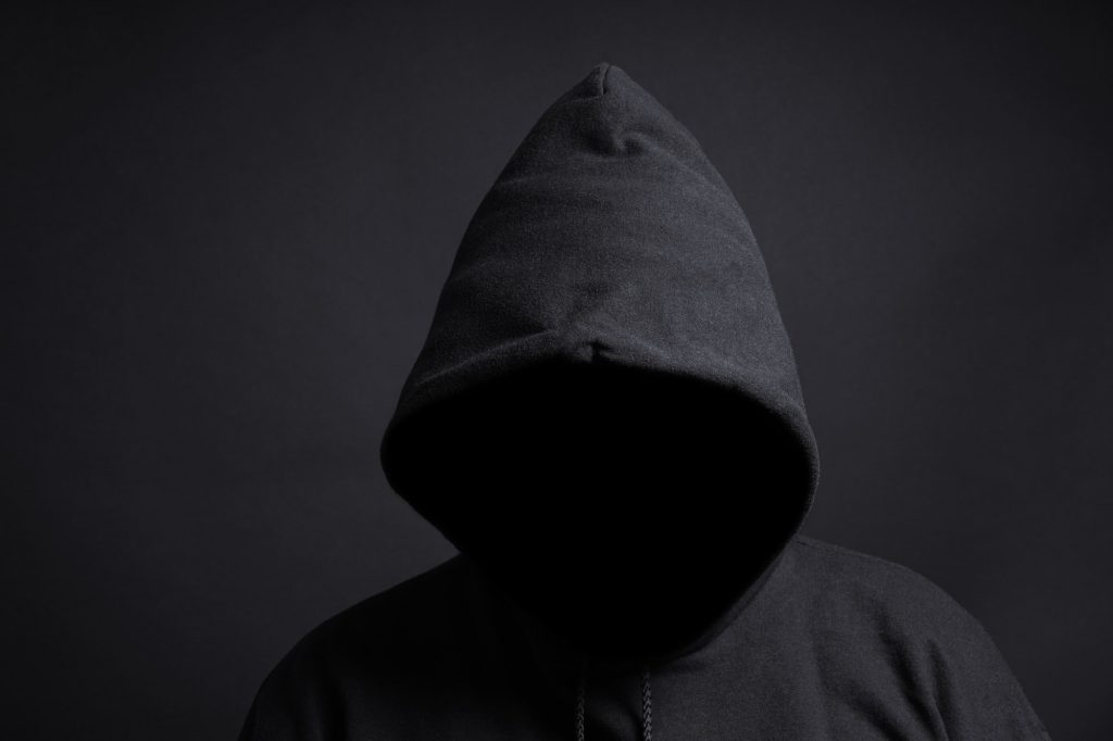 anonymous person with black hoodie and unrecognizable face hidden in shadow